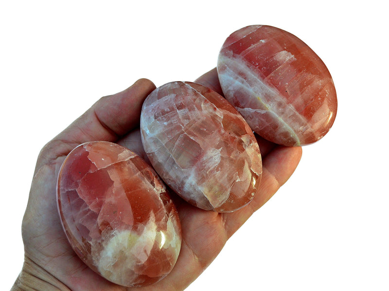 Three rose calcite palm stones 50mm-65mm on hand with white background