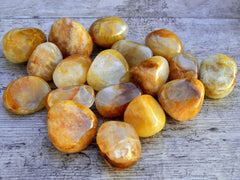 Several chunky yellow hematoid quartz tumbled on wood table