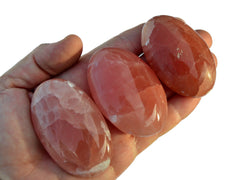 Three rose calcite palm stones 65mm-75mm on hand with white background