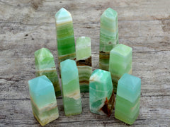 Several green banded pistachio calcite obelisks crystals 125mm-155mm on wood table