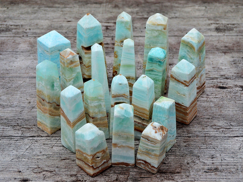 Several caribbean blue calcite faceted crystals points on wood table