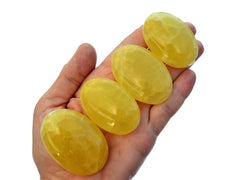 Four lemon calcite palm stones 45mm-60mm on hand with white background