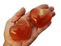Three honey calcite crystal hearts 50mm-55mm on hand with white background