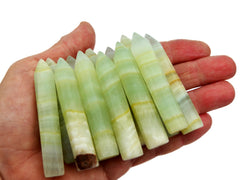 Some green pistachio calcite generator points 65mm-70mm on hand with white background