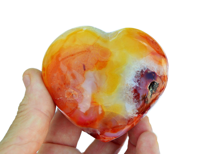One orange carnelian heart crystal 65mm on hand with white background
