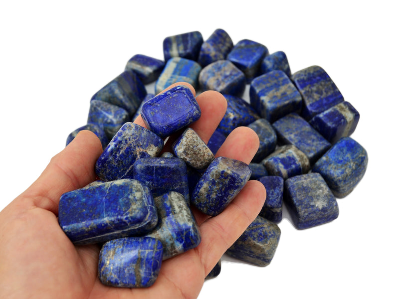 Some lapis lazuli mini tumbled minerals on hand with background with several stones on white