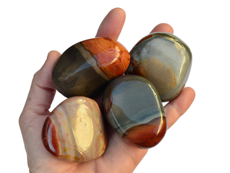 Four large polychrome jasper tumbled crystals on hand with white background