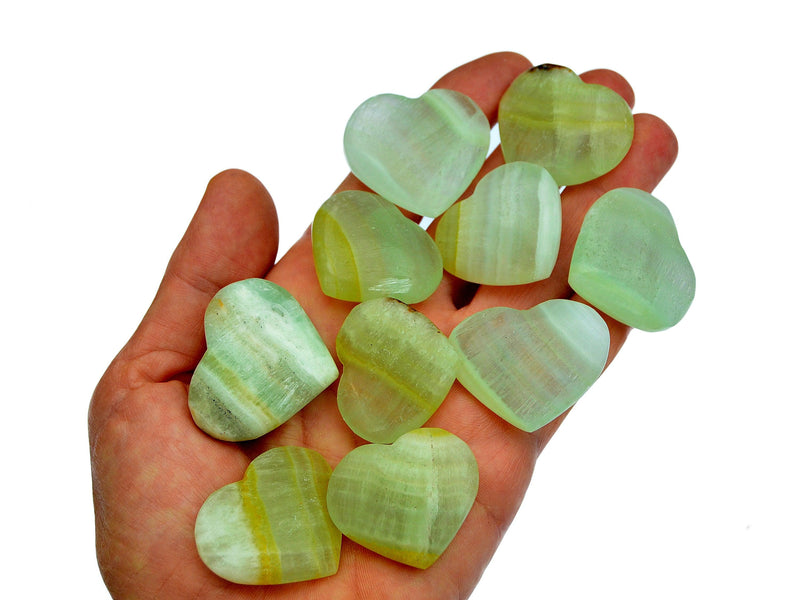 Green pistachio calcite hearts 35mm-40mm on hand with white background