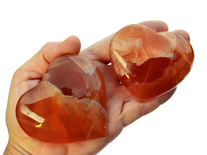 Three honey calcite heart crystals 65mm-75mm on hand with white background