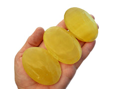 Three lemon calcite palm stones 55mm-70mm on hand with white background