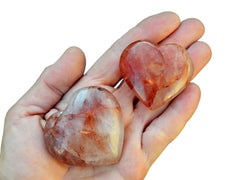Two fire quartz crystal hearts 40mm-50mm on hand with white background