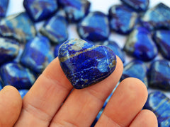 One lapis lazuli heart mineral 30mm on hand with background with several crystals on white