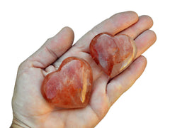 Two hematoid quartz crystal hearts 40mm-50mm on hand with white background