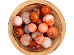 Several carnelian crystal spheres 25mm-40mm inside a wood bowl on white background