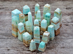 Several caribbean blue calcite crystal towers different sizes on wood table