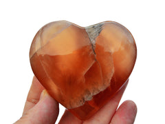 One honey calcite heart shaped crystal 75mm on hand with white background
