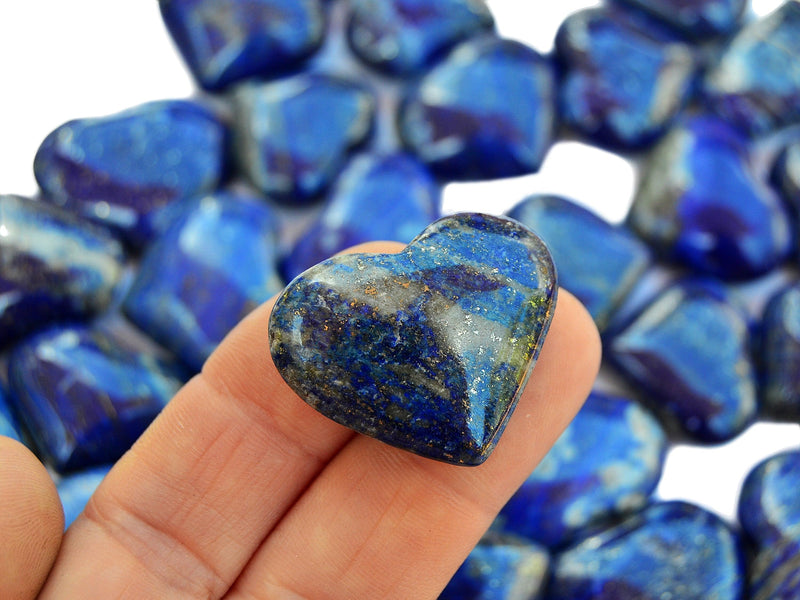 One lapis lazuli heart mineral 30mm on hand with background with several crystals on white