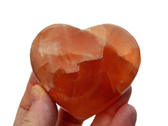 One honey calcite crystal heart 60mm on hand with white background