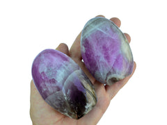 Two large amethyst free form stones on hand with white background