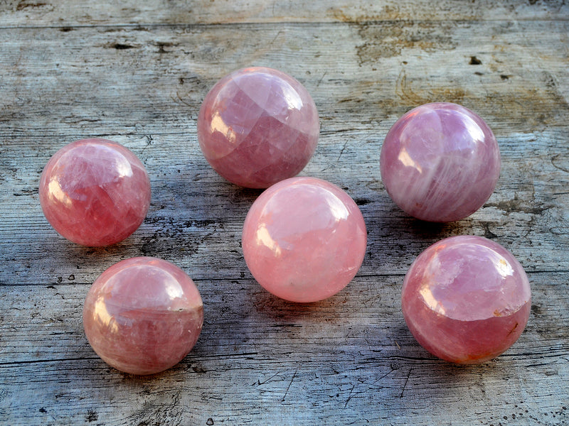 Six pink quartz crystal balls 70mm-75mm on wood table