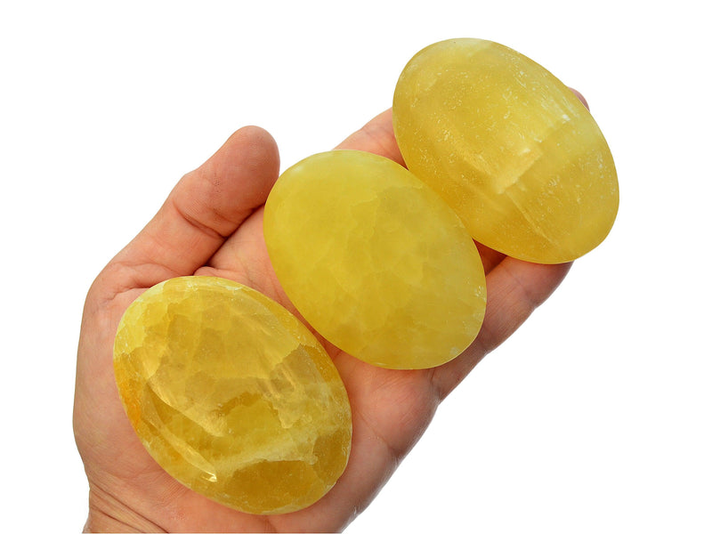 Three lemon calcite palm stones 60mm-70mm on hand with white background