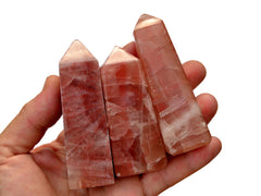 Three pink calcite crystal towers 70mm-80mm on hand with white background