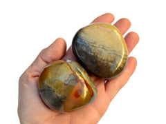Two large desert jasper tumbled crystals on hand with white background