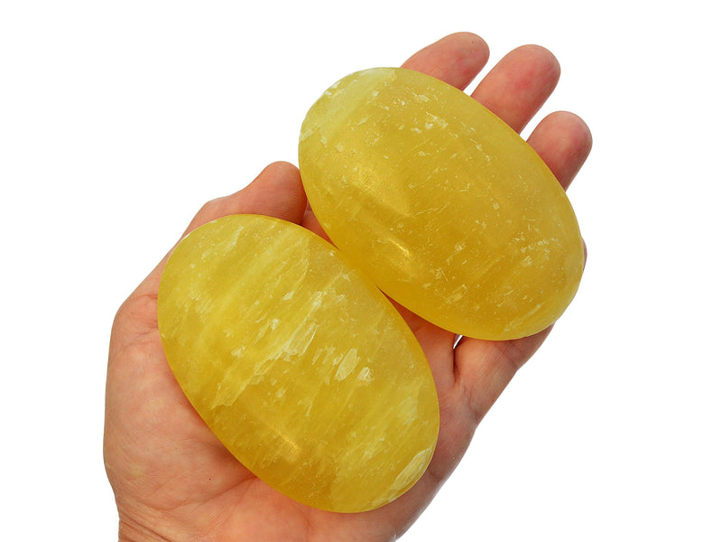 Two large lemon calcite palm crystals 80mm on hand with white background