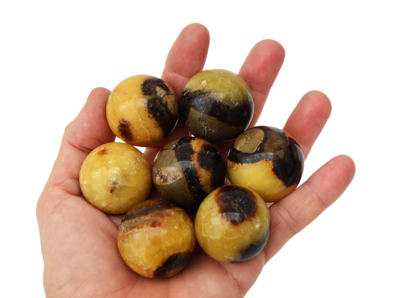 Some septarian crystal spheres 30mm on hand with white background