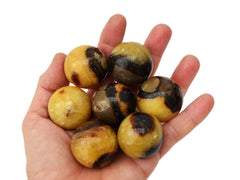 Some septarian crystal spheres 30mm on hand with white background