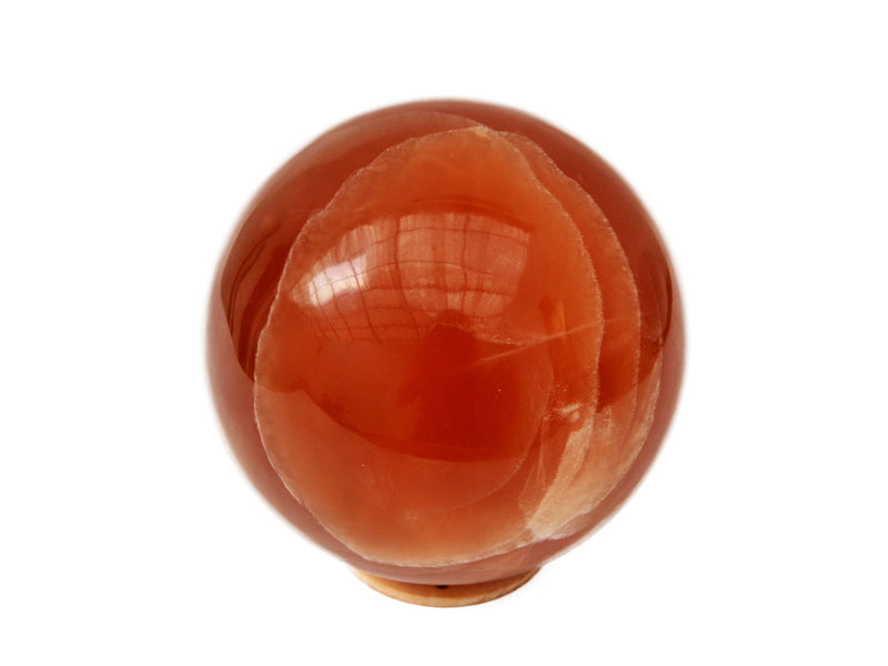 Big honey calcite sphere crystal 85mm on hand with white background