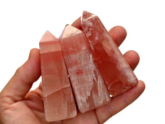Three pink calcite towers 70mm-80mm on hand with white background
