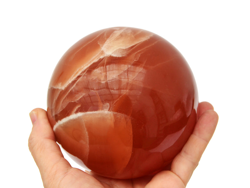 Large honey calcite sphere crystal 90mm on hand with white background