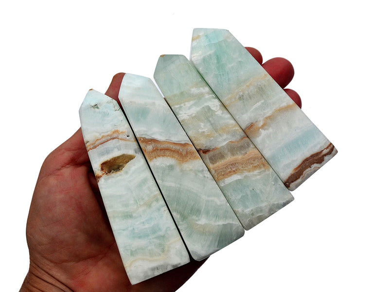 Four caribbean calcite crystal faceted points 80mm-110mm on hand with white background