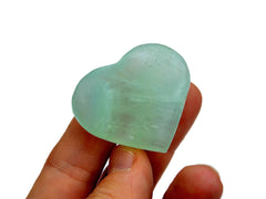 One small pistachio calcite heart 40mm on hand with white background