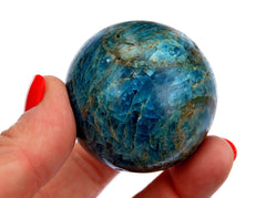 One blue apatite sphere stone 50mm on hand with white background