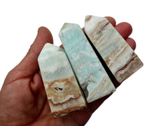 Four caribbean calcite crystal obelisks 65mm-70mm on hand with white background