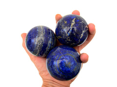 Three lapis lazuli spheres 60mm-65mm on hand with white background