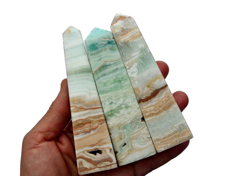 Three caribbean calcite crystal obelisk 100mm-110mm on hand with white background