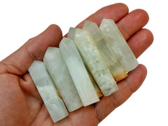 Some blue green caribbean calcite faceted crystal points 55mm-60mm on hand with white background