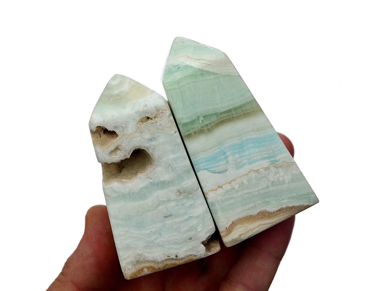 Four caribbean calcite crystal towers 60mm-70mm on hand with white background