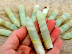Two pistachio calcite faceted points 70mm on hand with background with some points