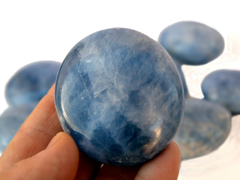 One blue calcite palm stone 60mm on hand with backgroud