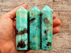 Three amazonite crystal towers 95mm on hand with wood background