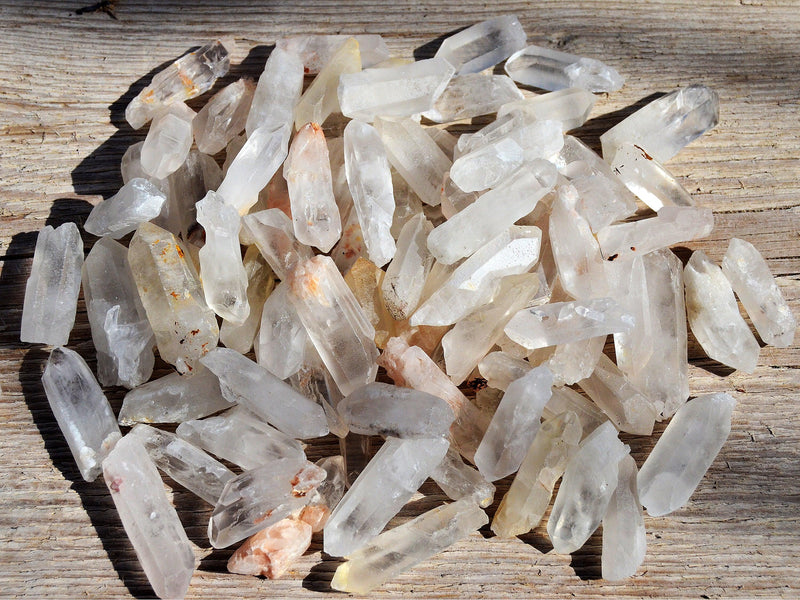 Several mini raw crystal quartz points on wood table