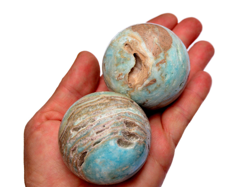 Two druzy blue aragonite crystal spheres 55mm on hand with white background
