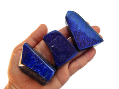 Three lapis lazuli free form crystals 45mm-60mm on hand with white background