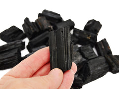 One raw black tourmaline cathedral 45mm on hand with background with some crystals on white