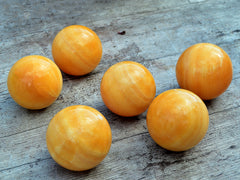 Several orange calcite spheres 55mm-65mm on wood table