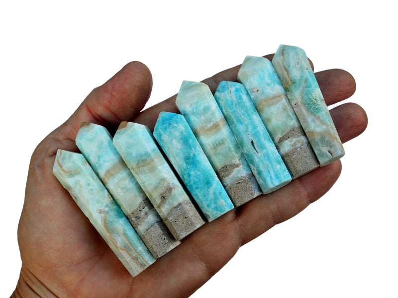 Eight small blue aragonite crystal towers 45mm-65mm on hand with white background